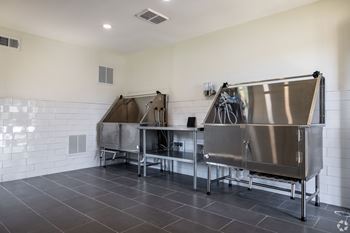 A large stainless steel tank is in the middle of a room with a white tiled wall.